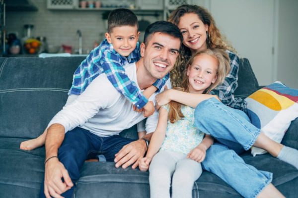 Smiling parents enjoying with their small children in the living room.